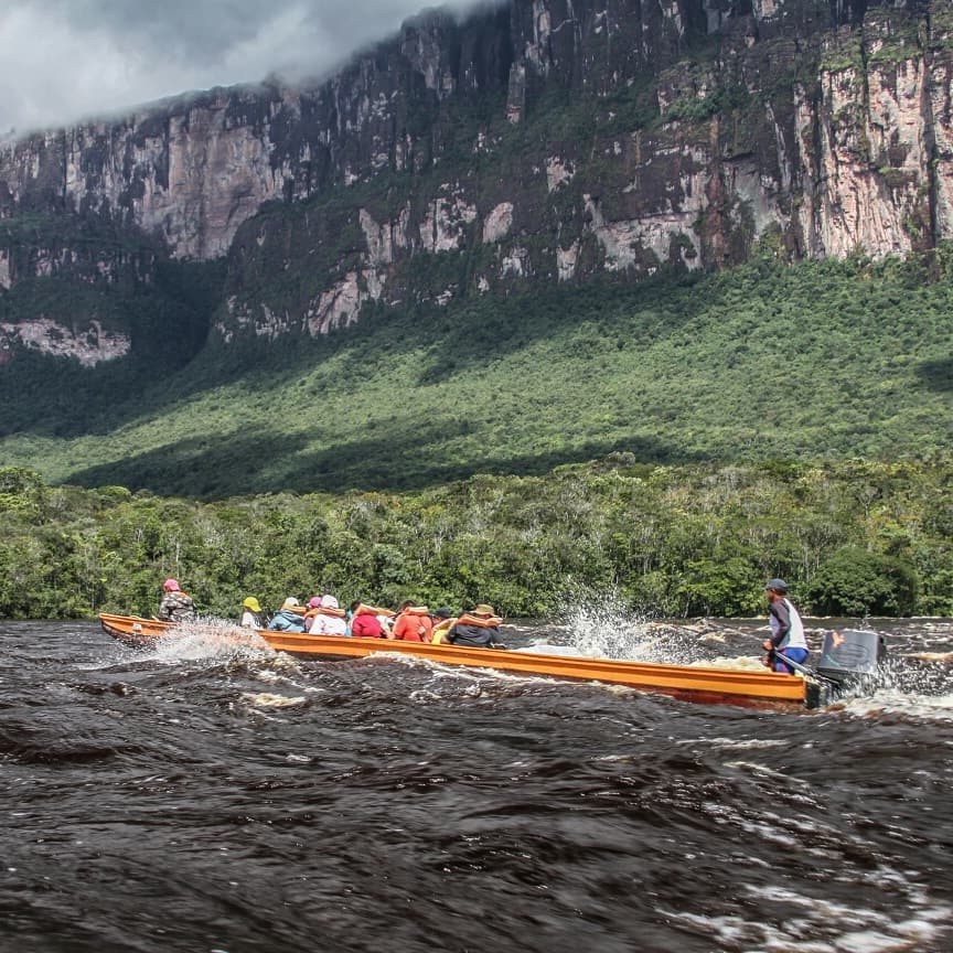 Viajeros en una curiara por el río, al pie de un tepuy.